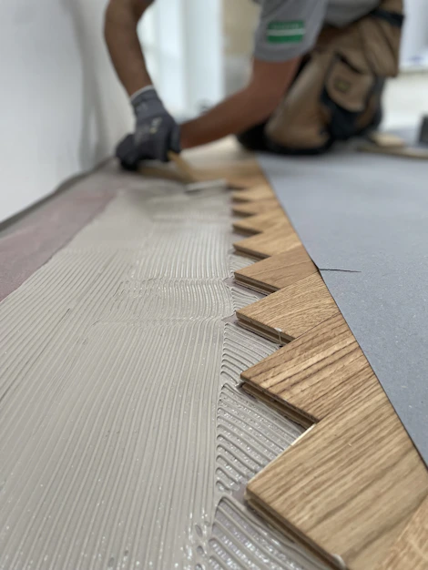 A skilled craftsman carefully installing elegant wooden flooring in a modern Lisbon apartment.