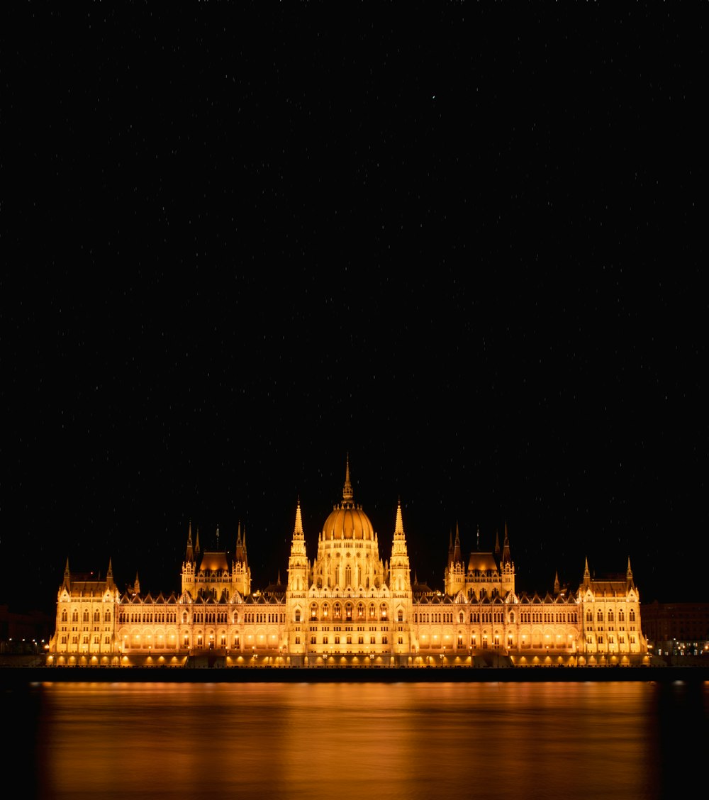 a large building lit up at night with water in front of it
