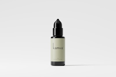 A black and cream-colored dropper bottle displayed against a plain white background. The bottle has a minimalist design with the text 'kanva' printed on it. Shadows are subtly cast beneath the bottle.