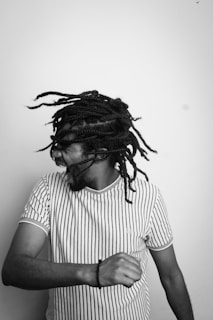 A person with braided hair is caught in mid-motion, suggesting dynamic movement. They are wearing a striped t-shirt and appear to be expressing joy or excitement.