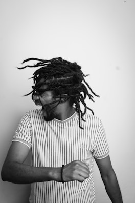 A person with braided hair is caught in mid-motion, suggesting dynamic movement. They are wearing a striped t-shirt and appear to be expressing joy or excitement.