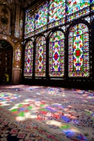Golden sunlight filtering through stained glass windows onto a plush maroon carpet.