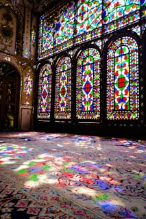 Golden sunlight filtering through stained glass windows onto a plush maroon carpet.