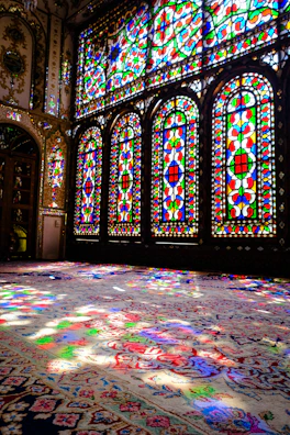 Wide shot of a bright room illuminated by large stained glass panels.