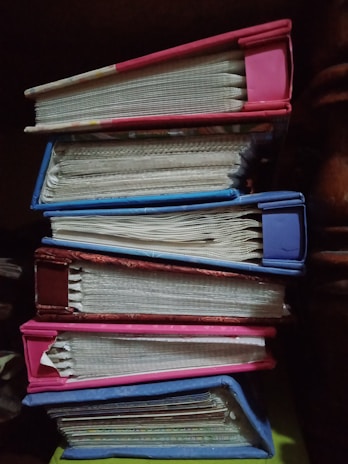 Stack of colorful books with handwritten notes peeking out from the pages.