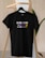 A black t-shirt hangs on a wooden hanger against a light-colored background. The t-shirt bears the text 'ENGINEER KI JAAN LOGE KYA?' in a mix of white, purple, and yellow fonts.