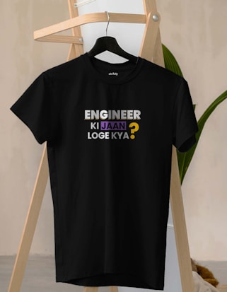 A black t-shirt hangs on a wooden hanger against a light-colored background. The t-shirt bears the text 'ENGINEER KI JAAN LOGE KYA?' in a mix of white, purple, and yellow fonts.