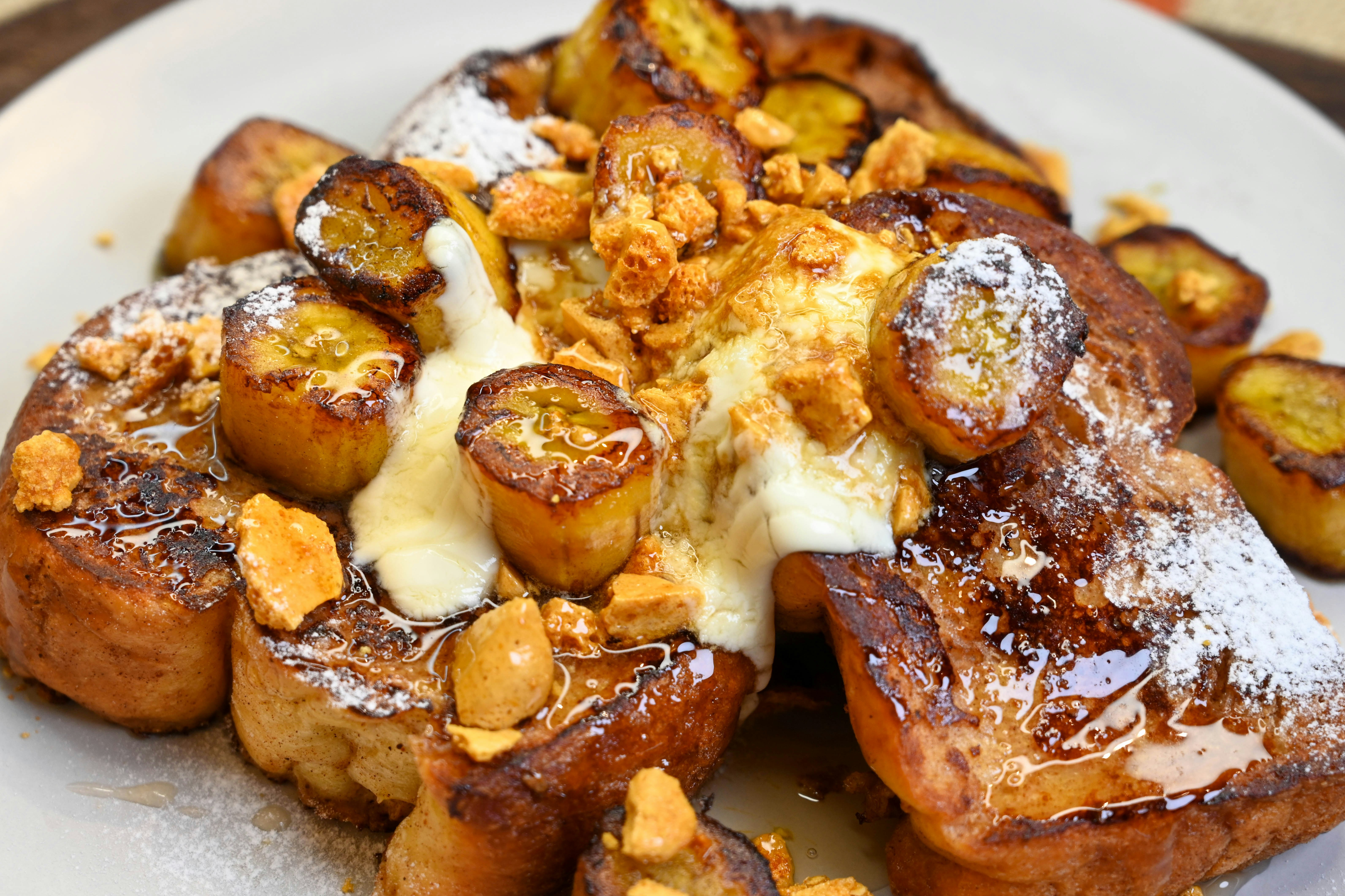 Un plato blanco cubierto con tostadas francesas cubiertas de azúcar en polvo