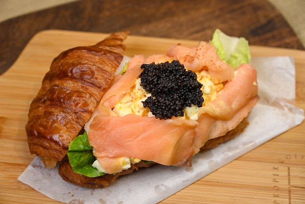 a croissant sandwich with salmon, eggs, and lettuce