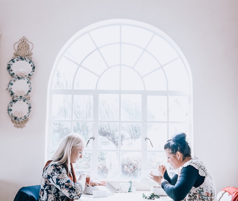 a couple of women sitting at a white table