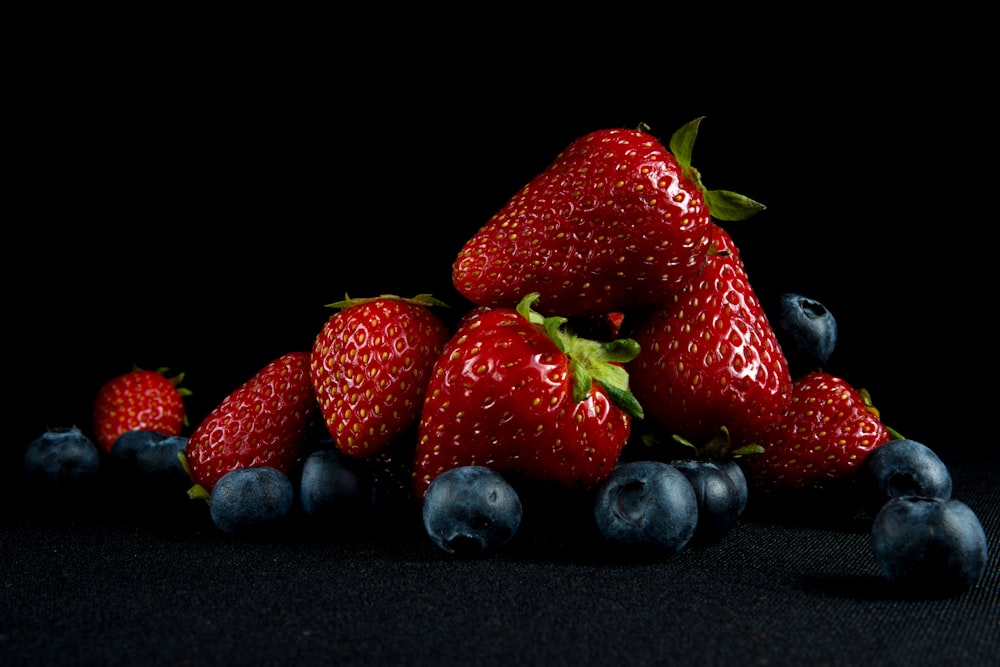 a pile of strawberries and blueberries on a black background