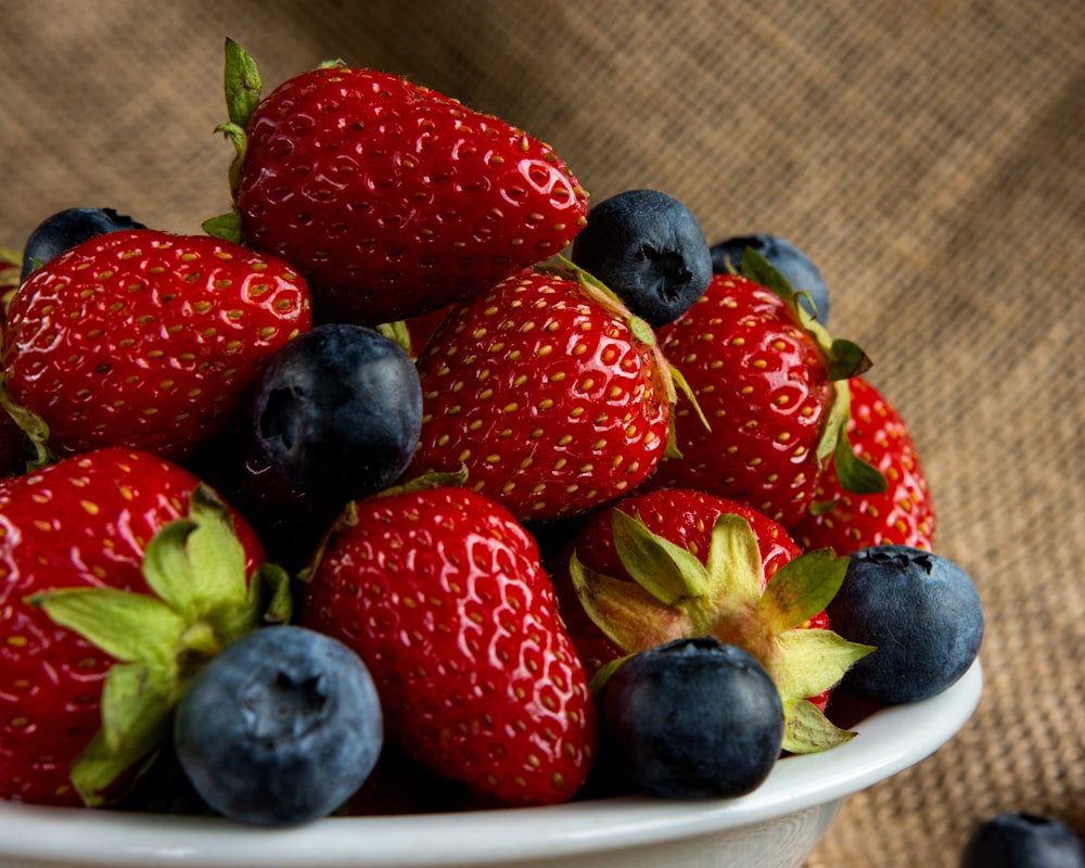 a white bowl filled with blueberries and strawberries