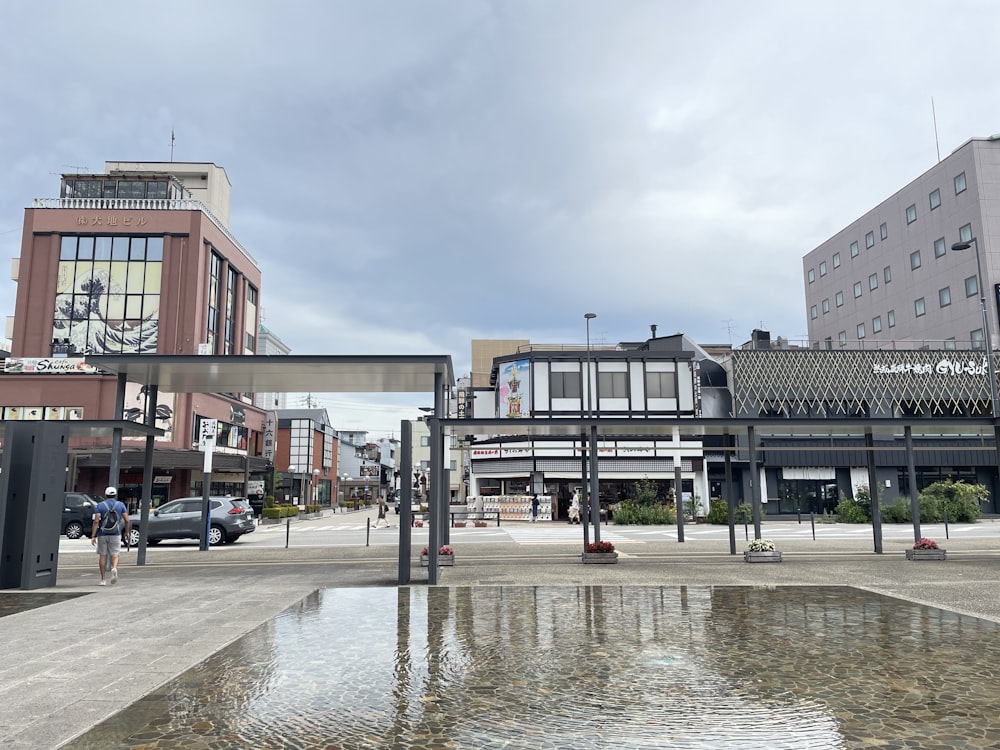 a city square with a fountain and people walking on the sidewalk