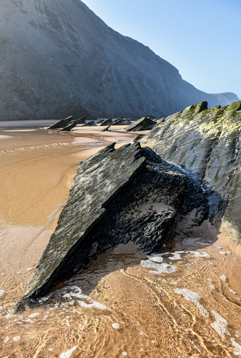 un gros rocher posé sur une plage de sable