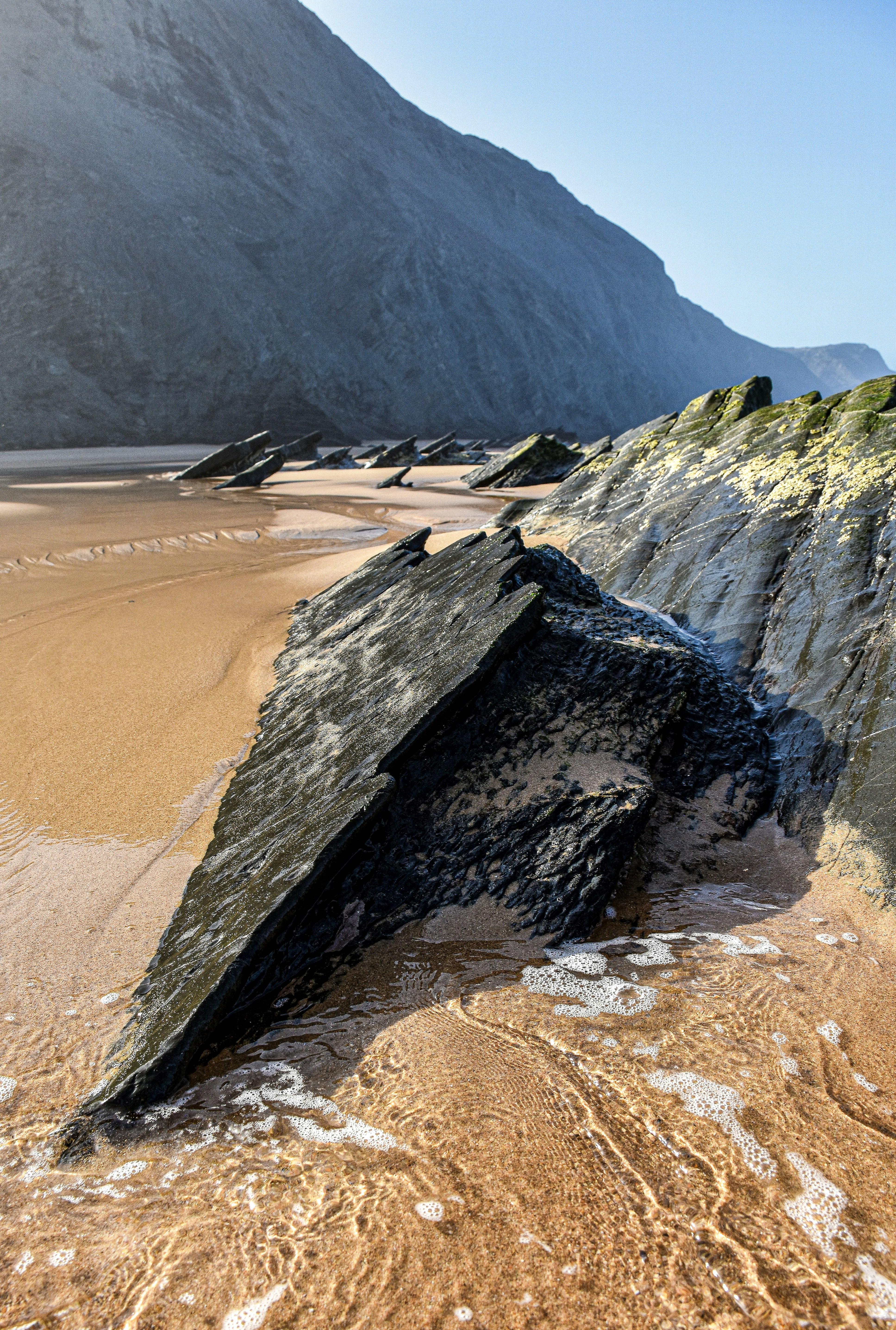 a large rock laying on top of a sandy beach