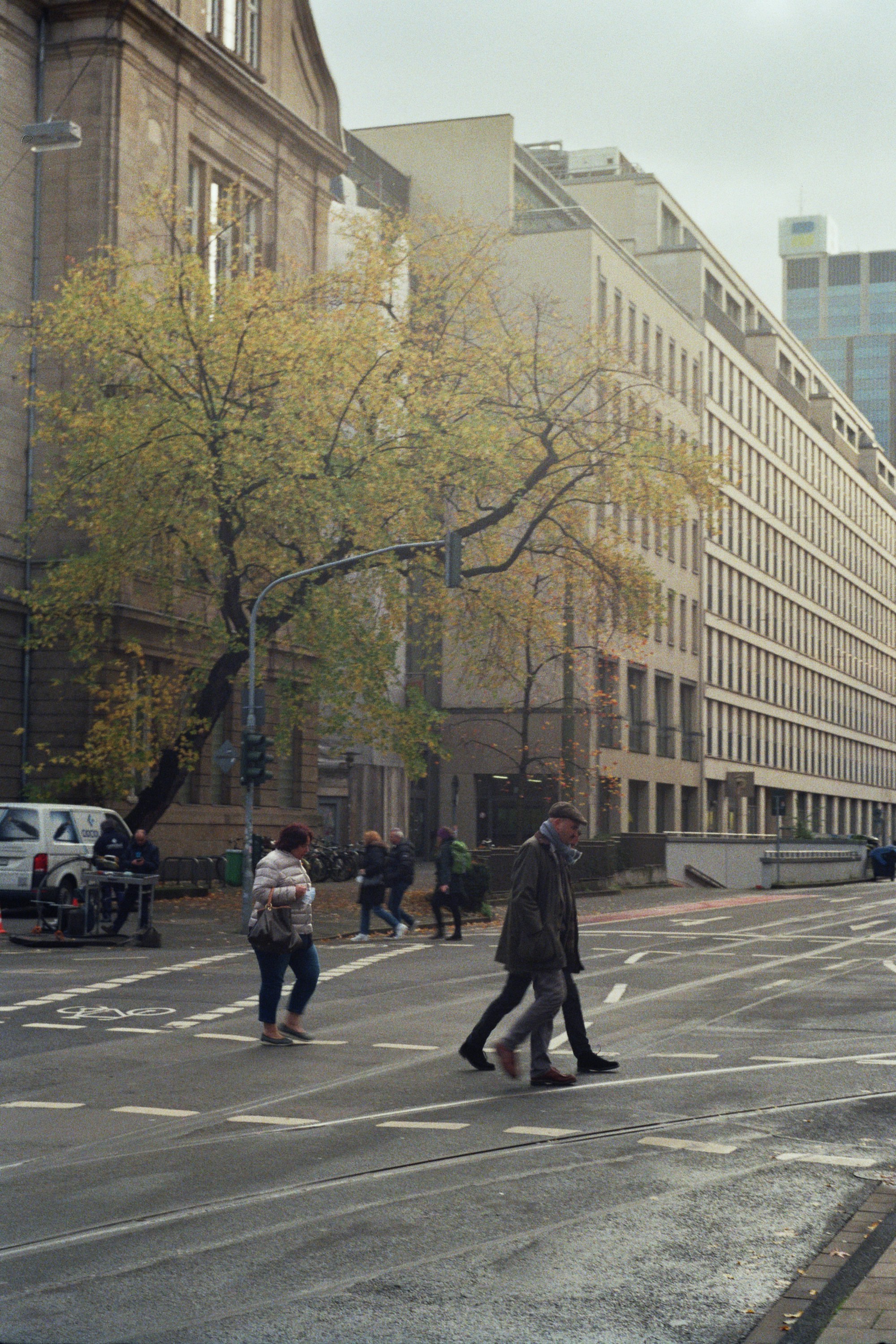 A group of people walking across a street next to tall buildings photo ...
