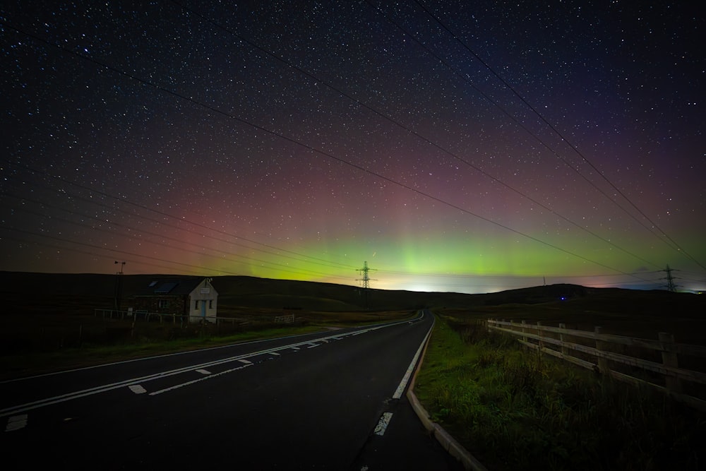 Una lunga strada con una luce verde e viola dell'aurora nel cielo
