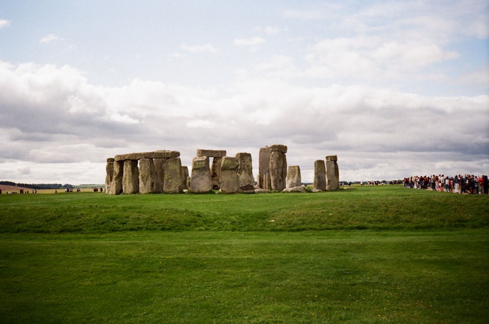a group of people standing around stonehenge in a field