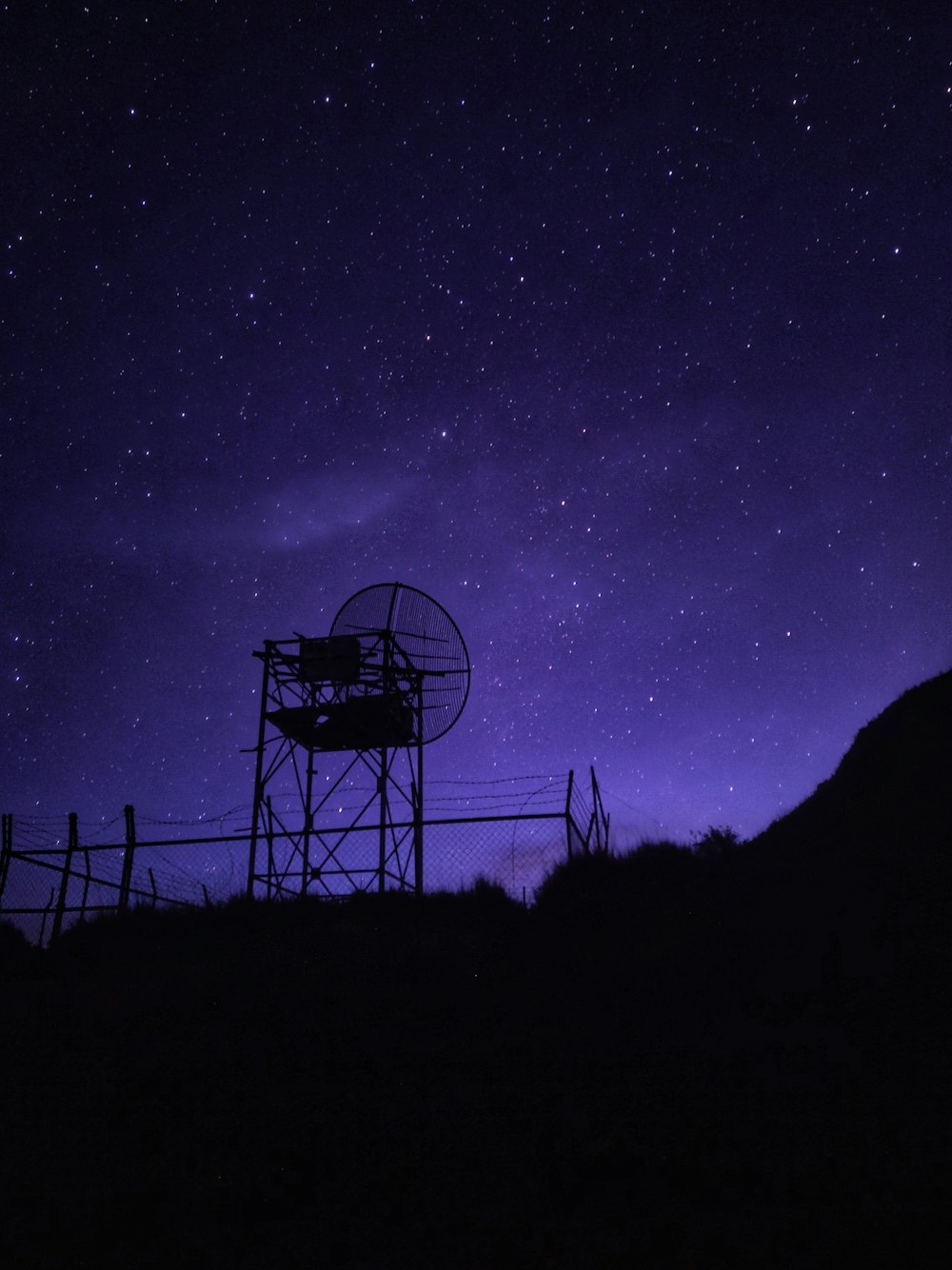 a night sky with stars and a silhouette of a tower