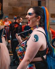 A young woman with bold party makeup, laughing joyfully at a festive event.