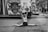 A cheerleader performs a split in front of a van decorated with a large logo and streamers. She holds pom-poms and smiles while other cheerleaders and people in the background can be seen. The setting appears to be an outdoor event or parade.