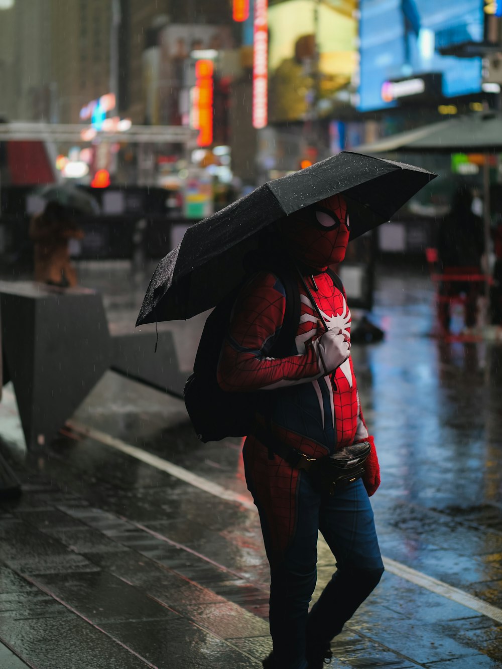 a man in a spider suit holding an umbrella
