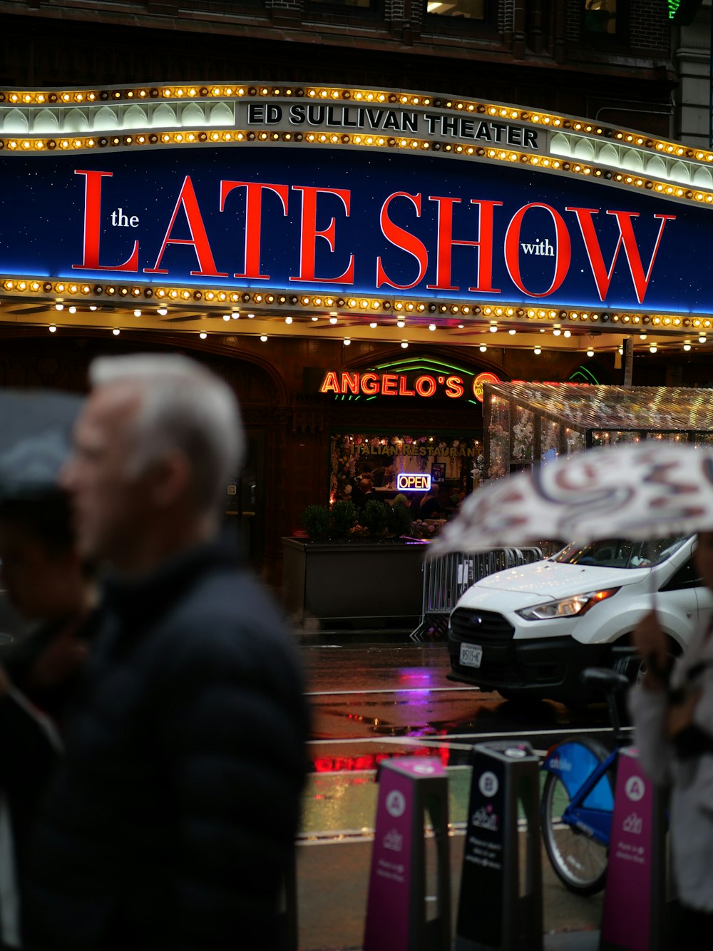 a man holding an umbrella in front of a theater