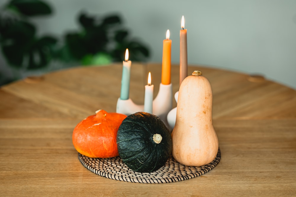 a wooden table topped with candles and a squash