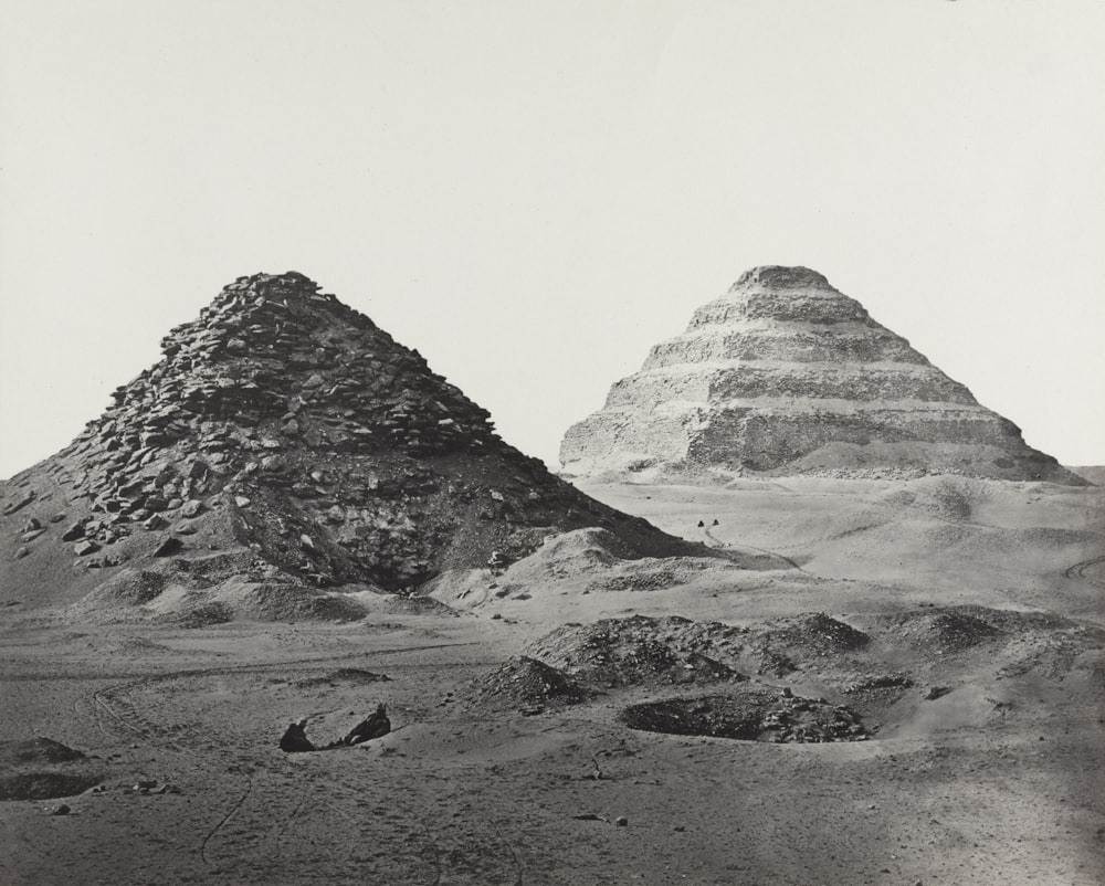 a black and white photo of two pyramids in the desert
