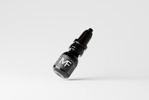 A black nasal spray bottle with a sleek design, featuring prominent white labeling and the letters 'MF' visible on the front. The bottle appears to be floating against a minimalist white background.