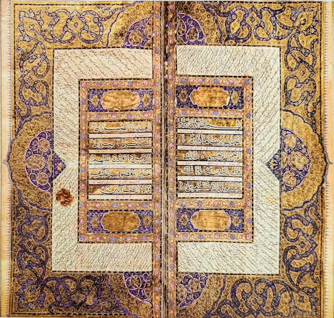 A close-up of an ancient manuscript page illuminated with gold leaf and intricate calligraphy.