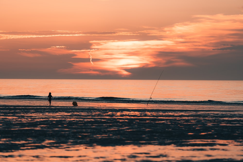 two people walking on the beach at sunset