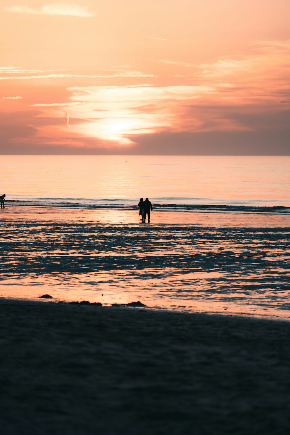 um casal de pessoas em pé em cima de uma praia