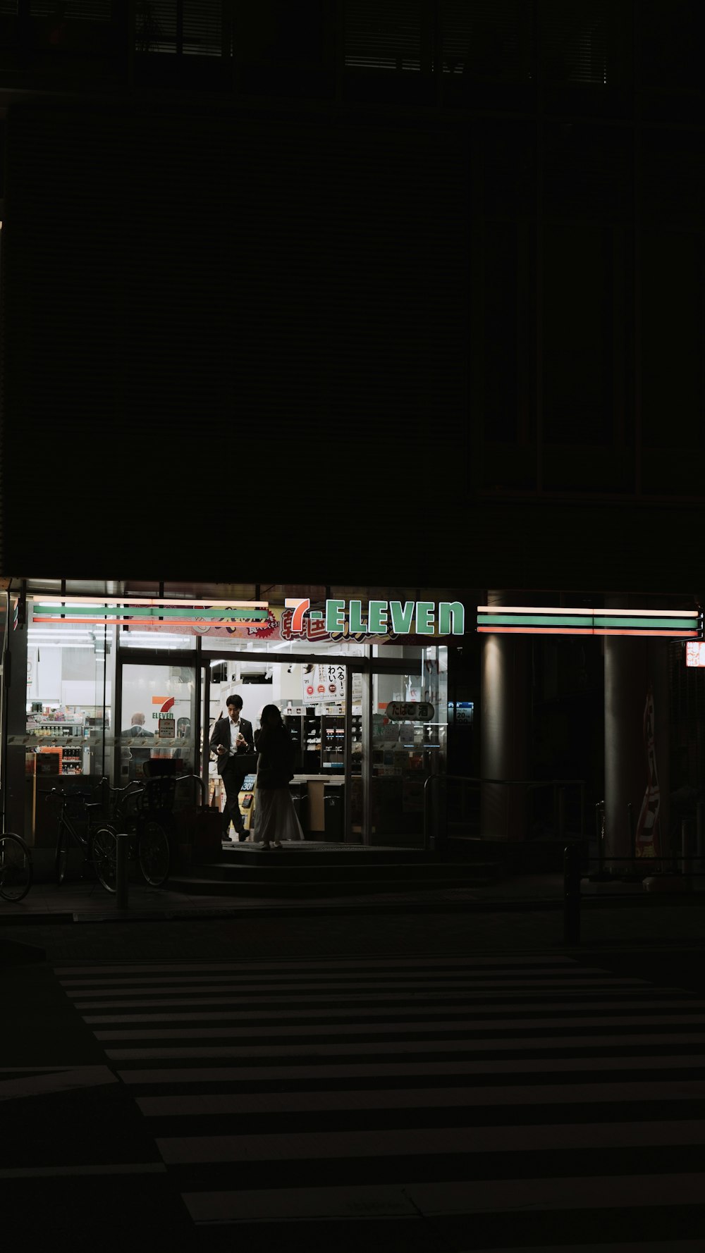 a group of people standing outside of a store at night