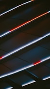 An abstract display of angled panels with LED lighting, featuring striking red and white lines against a dark background, creating a sense of movement and modernity.