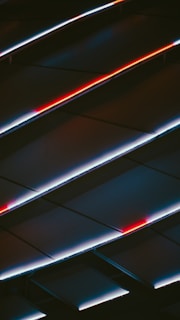 An abstract display of angled panels with LED lighting, featuring striking red and white lines against a dark background, creating a sense of movement and modernity.