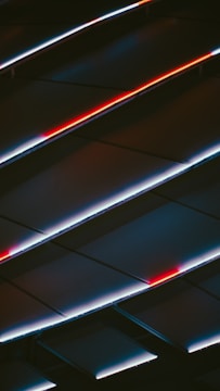 An abstract display of angled panels with LED lighting, featuring striking red and white lines against a dark background, creating a sense of movement and modernity.