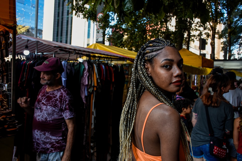 a woman with braids standing in front of a market
