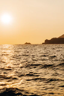 A serene view of the turquoise waters surrounding Lobos Island with the sun casting golden hues over the gentle waves.