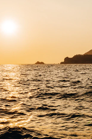 A serene view of the turquoise waters surrounding Lobos Island with the sun casting golden hues over the gentle waves.
