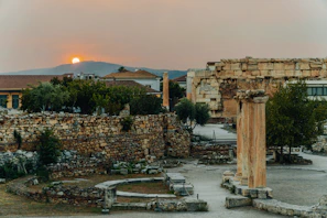 Ancient Greek ruins bathed in golden sunlight at sunset.