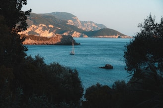 A calm sea scene with a boat gently floating near the cliffs of Calvià, framed by lush greenery.