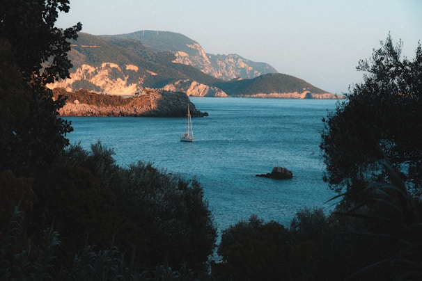 A calm sea scene with a boat gently floating near the cliffs of Calvià, framed by lush greenery.