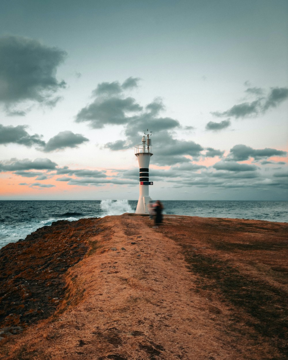 a person standing on a dirt road next to the ocean