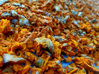 Close-up of vibrant turmeric powder (haldi) with pumpkin and sunflower seeds scattered around.