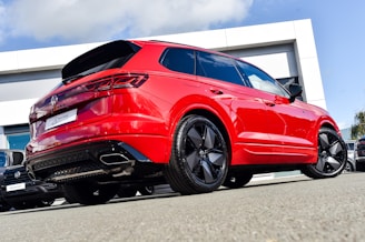 A bold red SUV with tinted windows, positioned on a clean lot with a clear blue sky backdrop.