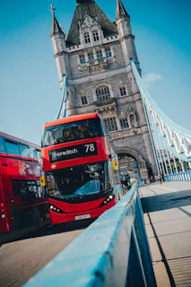 The classic red double-decker buses crossing Tower Bridge in London on a sunny day
