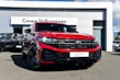 A bright red Volkswagen SUV is prominently displayed in front of a dealership with a sign reading 'Crewe Volkswagen.' The car has sleek black rims and a modern grill design, parked on a paved surface. Other vehicles are showcased in the background, contributing to a professional automotive setting.