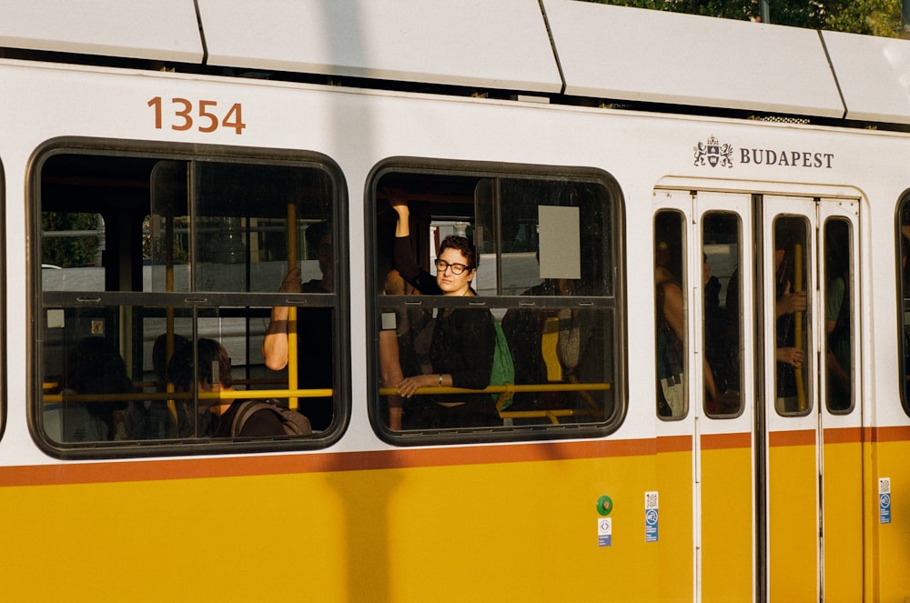 a group of people sitting on a yellow and white bus