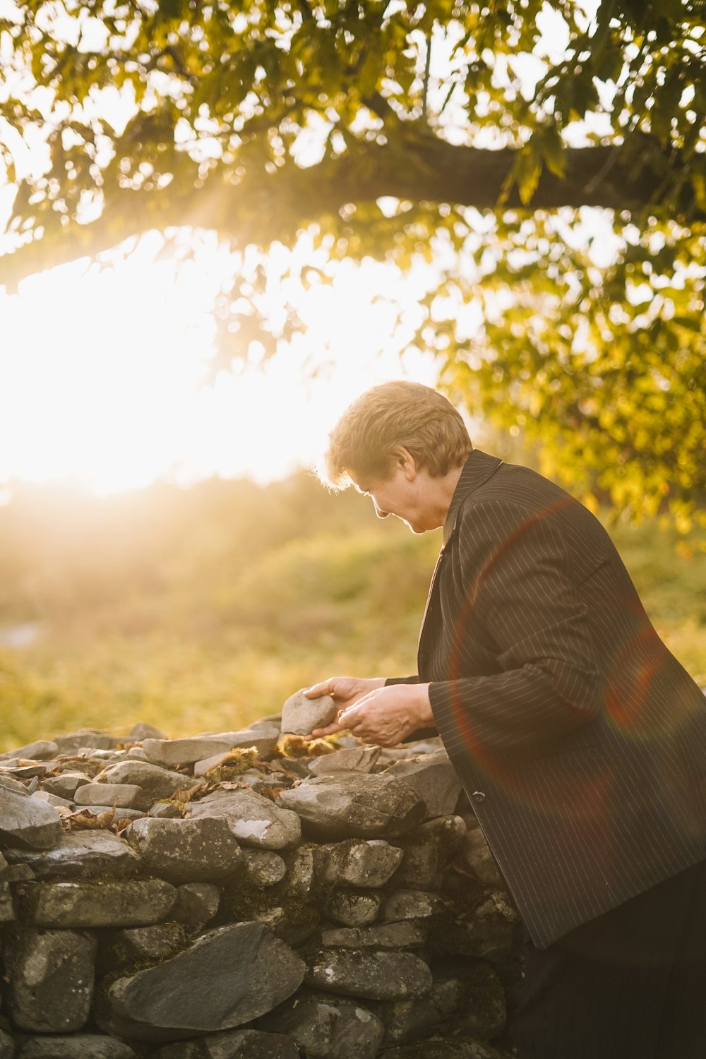 a man in a suit leaning on a stone wall